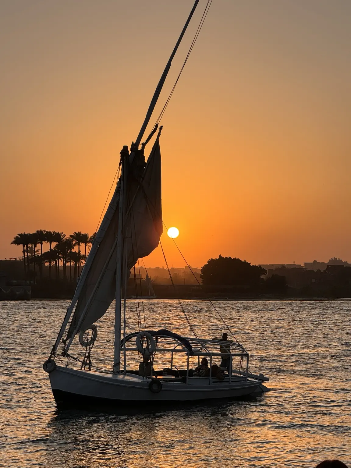 A felucca sailing on the Nile as the sun sets