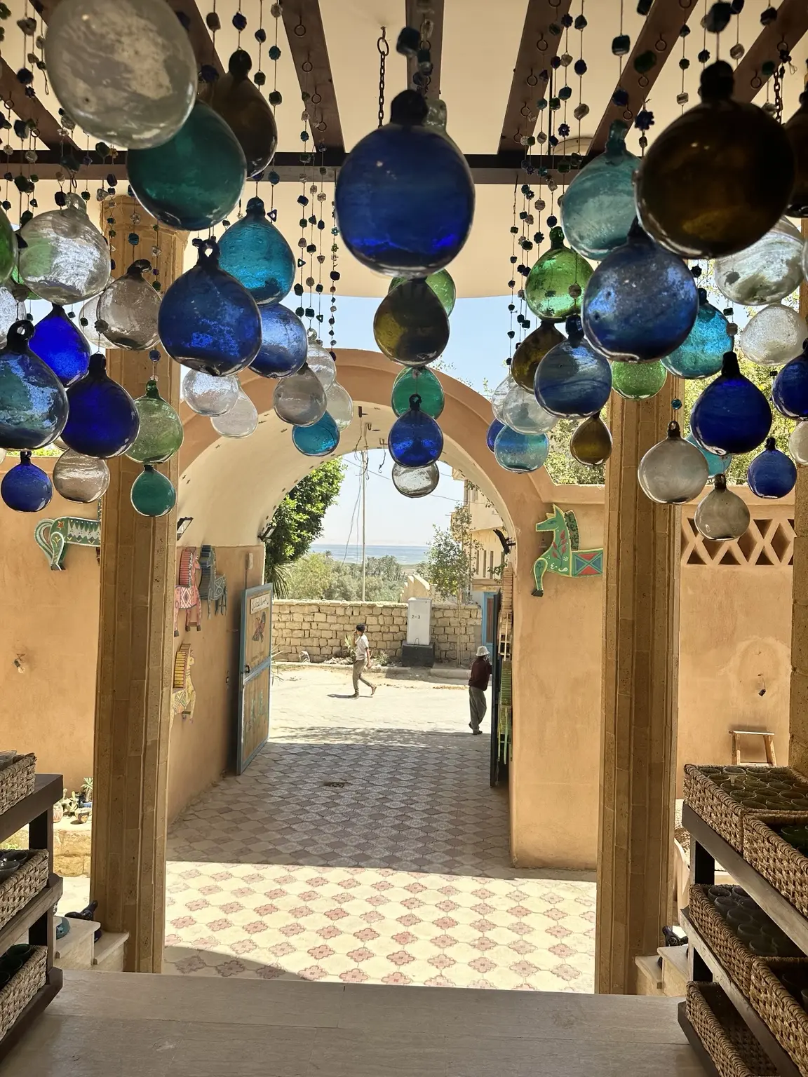Blue glass ornaments hanging above the entrance to an Egyptian village courtyard