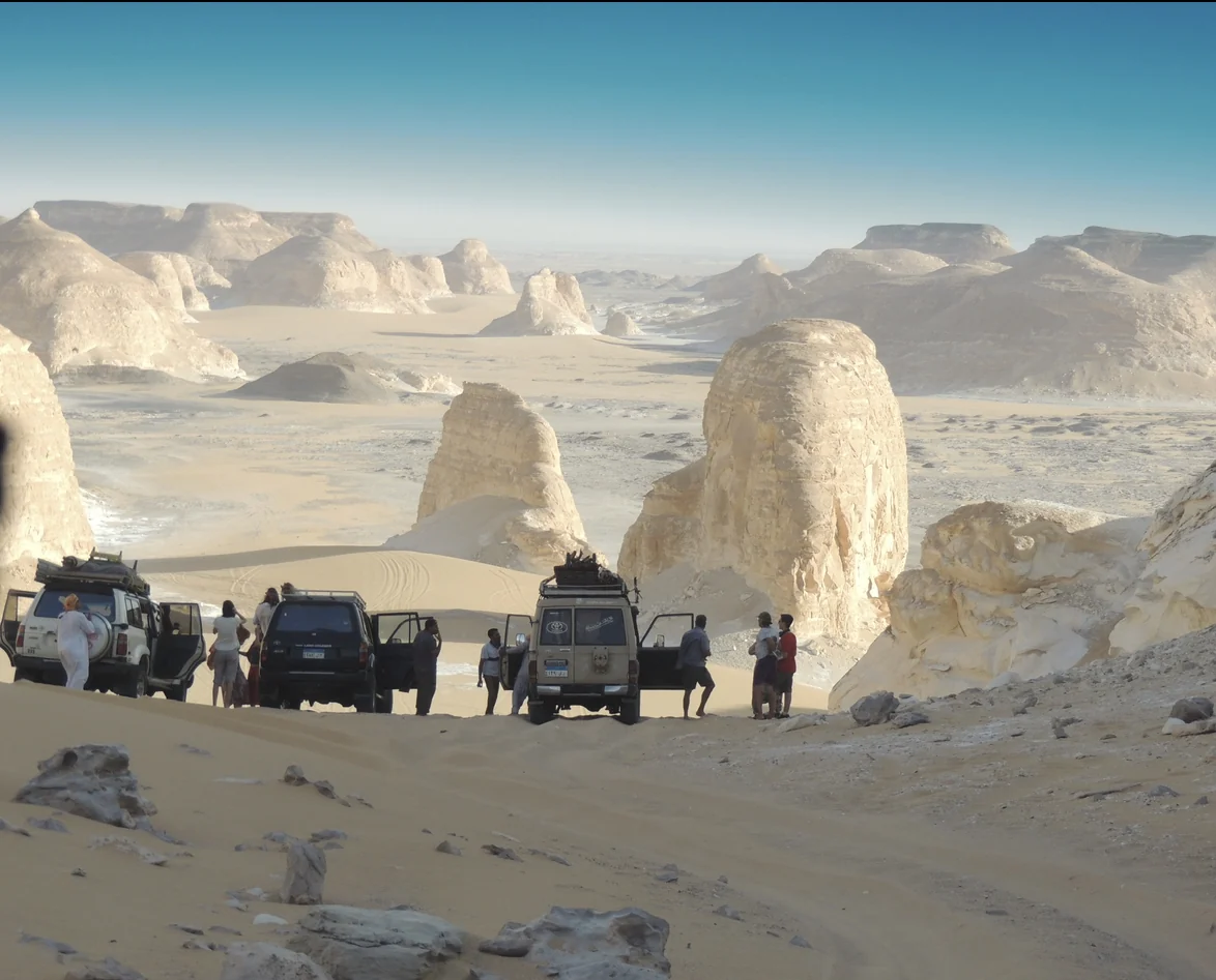 Travellers and four-wheel-drive vehicles among the chalk formations of Egypt’s White Desert